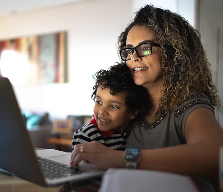 Mom doing research on her laptop while holding her son.