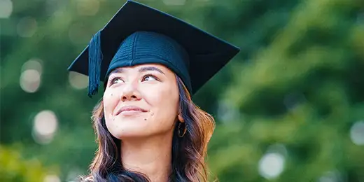 female with graduation cap looking over