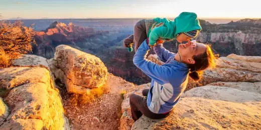 mother holding child up with canyon in the background