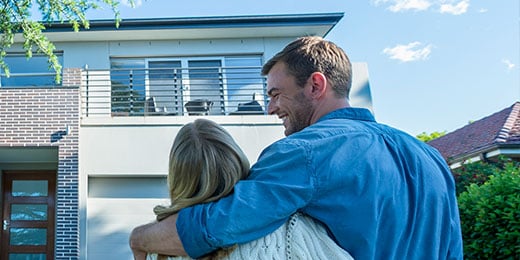 couple embracing in front of house