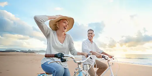 old couple riding bicycles on the beach