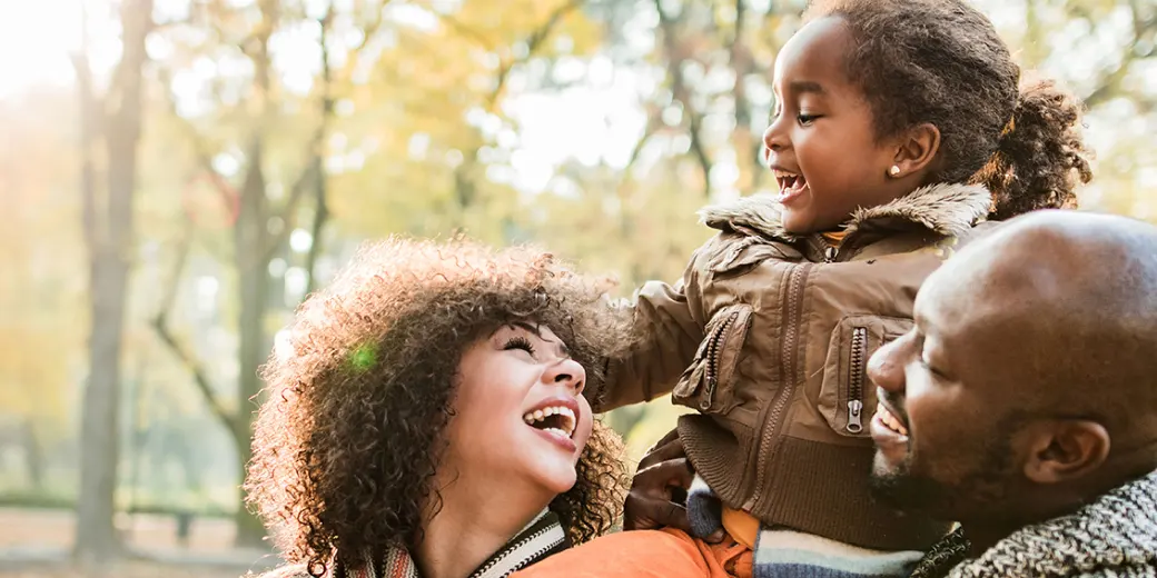 family playing in autumn leaves