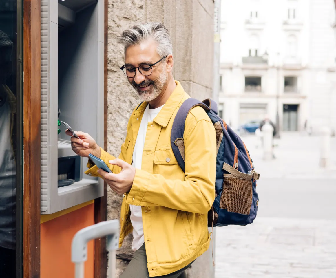 Man at ATM looking at his phone