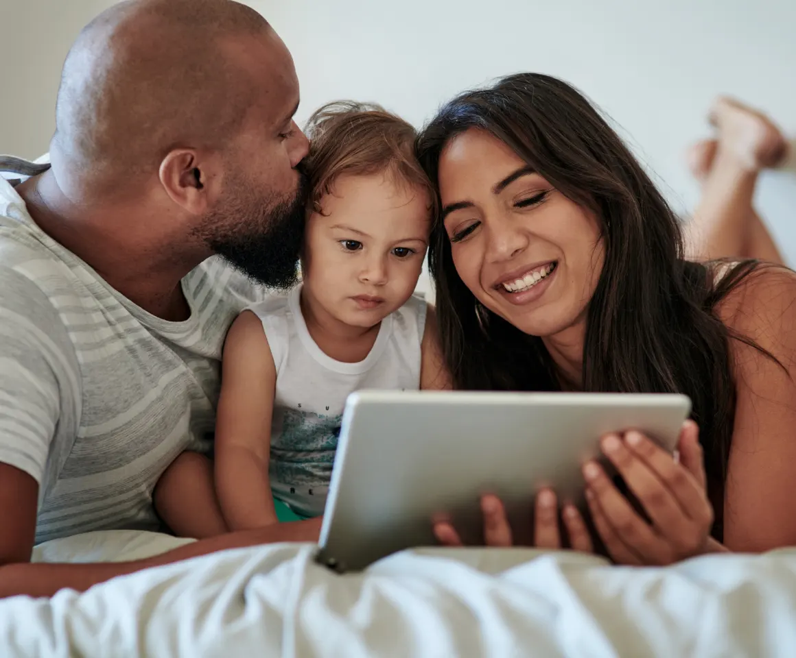 family on bed looking at tablet